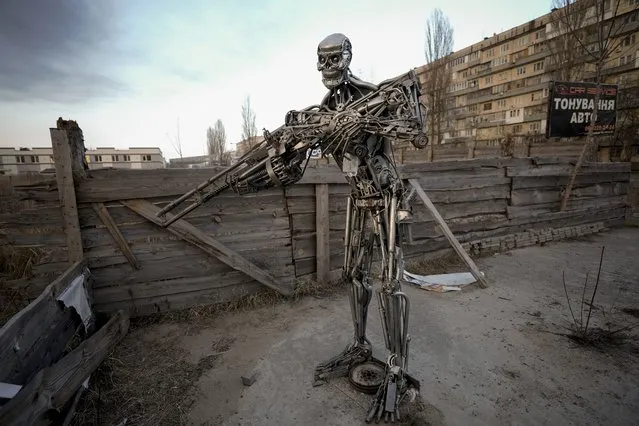 A depictions of the Terminator, made from automobile transmission parts, is placed near a checkpoint in Kyiv, Ukraine, Friday, March 25, 2022. About 300 people were killed in the Russian airstrike last week on a Mariupol theater that was being used as a shelter, Ukrainian authorities said Friday in what would make it the war's deadliest known attack on civilians yet. (Photo by Vadim Ghirda/AP Photo)