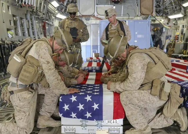 In this image provided by the U.S. Marine Corps, U.S. service members assigned to Joint Task Force-Crisis Response, and serving as pallbearers, kneel during a ramp ceremony on Friday, August 27, 2021, for the service members killed in action during operations at Hamid Karzai International Airport in Kabul, Afghanistan. (Photo by U.S. Marine Corps via AP Photo)