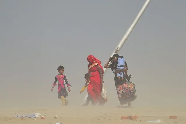 Women walk during a dust storm at the Sangam, the confluence of the rivers Ganges, Yamuna and mythical Saraswati, in Allahabad on on March 29, 2022. (Photo by Sanjay Kanojia/AFP Photo)
