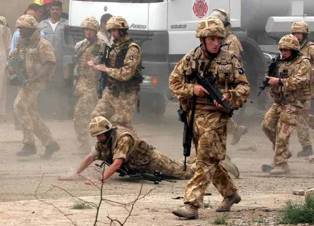 In this May 6, 2006 file photo, a British trooper falls after apparently being hit by a rock, as British troops move towards a helicopter crash site in Basra, Iraq's second-largest city, 550 kilometers (340 miles) southeast of Baghdad. Britain’s prime minister announced plans on October 4, 2016 to protect British troops from dubious legal claims made during conflicts. (Photo by Nabil Al-Jurani/AP Photo)
