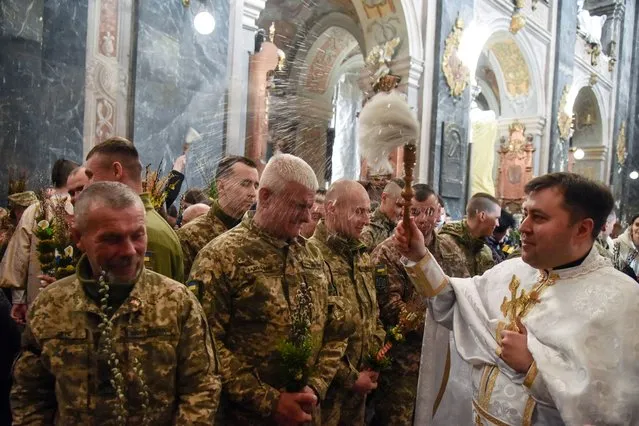 Ukrainian servicemen are sprinkled with holy water as they attend the consecration of the willow branches on Palm Sunday, amid Russia's invasion, at a church in Lviv, Ukraine on April 17, 2022. (Photo by Pavlo Palamarchuk/Reuters)