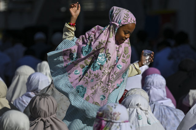 A child walks past people praying for rain during special prayers, known as Salat al-Istisqa, at Rahmatullah mosque in Lhoknga, Aceh province on July 18, 2024. (Photo by Chaideer Mahyuddin/AFP Photo)