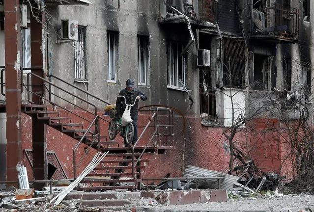 A man walks downstairs outside a residential building damaged during Ukraine-Russia conflict in the southern port city of Mariupol, Ukraine on April 21, 2022. (Photo by Alexander Ermochenko/Reuters)