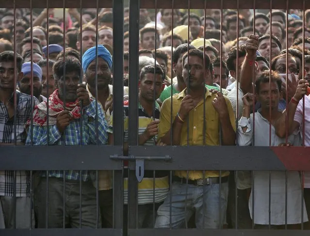 Onlookers stand at the gate of a police station where a gunfight took place inDinanagar town in Gurdaspur district of Punjab, India, July 27, 2015. (Photo by Mukesh Gupta/Reuters)