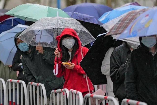 Residents with umbrellas line up in the rain for COVID testing at a commercial office complex on Wednesday, April 27, 2022, in Beijing. (Photo by Andy Wong/AP Photo)