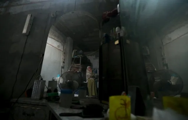 A Palestinian woman is reflected in a mirror as she stands inside her house during power cut at Shatti (beach) refugee camp in Gaza City July 23, 2015. (Photo by Mohammed Salem/Reuters)