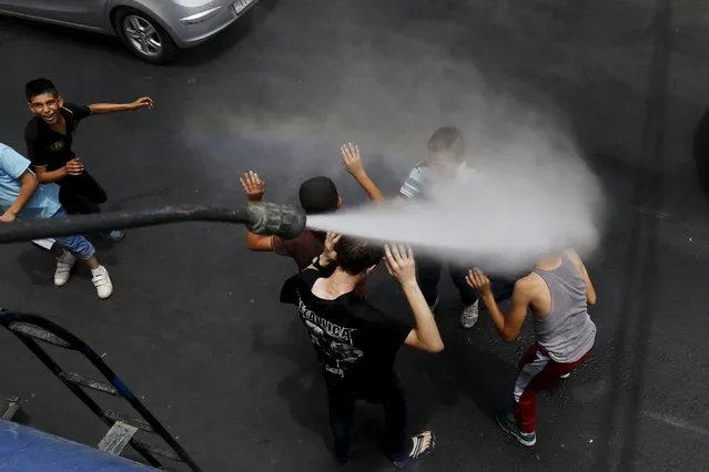 Children react as Greater Amman Municipality personnel spray them with a water sprinkler in order to cool them down as part of measures to ease the effect of a heatwave, in Amman, Jordan, August 3, 2015. (Photo by Muhammad Hamed/Reuters)