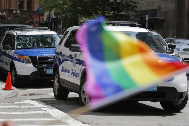 A man waves a rainbow flag in front of two Boston Police vehicles outside a Pride Month block party in Boston, Massachusetts, U.S. June 12, 2016 the same day as the mass shooting at Orlando's Pulse nightclub. (Photo by Brian Snyder/Reuters)