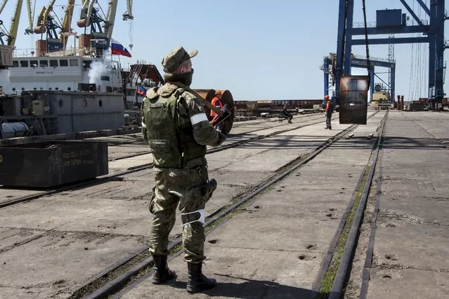 A Russian serviceman guards an area during the loading off rolled steel onto a Russian vessel at the Mariupol Sea Port in Mariupol, in territory under the government of the Donetsk People's Republic, eastern Ukraine, Monday, May 30, 2022. It marked the first time that a commercial ship used the port of Mariupol since the start of the Russian military action in Ukraine. (Photo by AP Photo/Stringer)