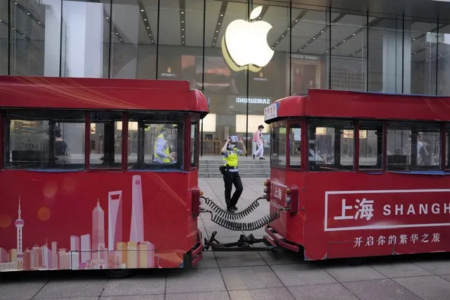 A police officer walks past a shuttered Apple store and advertising for Shanghai city, Wednesday, June 1, 2022, in Shanghai. (Photo by Ng Han Guan/AP Photo)