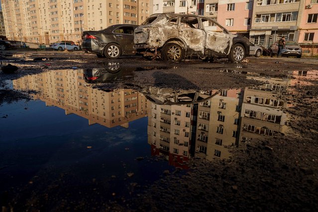 Destroyed cars are reflected in a pool of water after a Russian airstrike on residential neighbourhood in Sumy, Ukraine, on Saturday, August 17, 2024. (Photo by Evgeniy Maloletka/AP Photo)