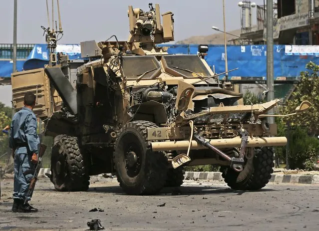 An Afghan policeman looks at the wreckage of an armoured vehicle of NATO-led International Security Assistance force (ISAF) at the site of a suicide attack in Kabul August 10, 2014. A suicide car bomber targeted a convoy of foreign forces in the capital Kabul on Sunday, killing at least four Afghan civilians, including children, and wounding dozens, Afghan security officials said. (Photo by Omar Sobhani/Reuters)