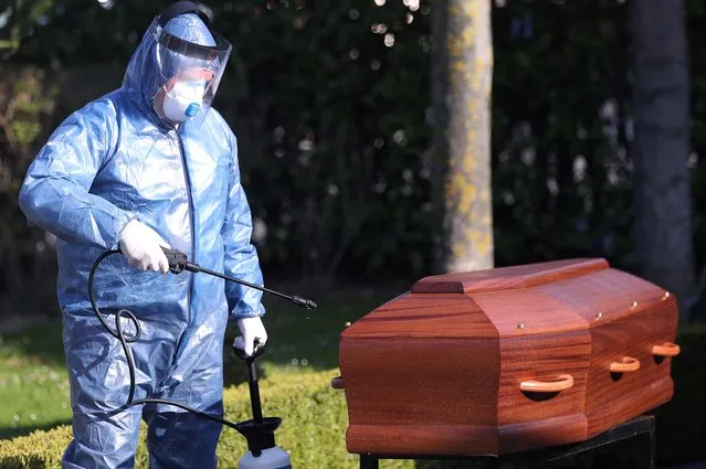 A mortuary worker sprays disinfectant on a coffin of a person who died of the coronavirus disease (COVID-19), near the city of Charleroi, Belgium on April 7, 2020. (Photo by Yves Herman/Reuters)