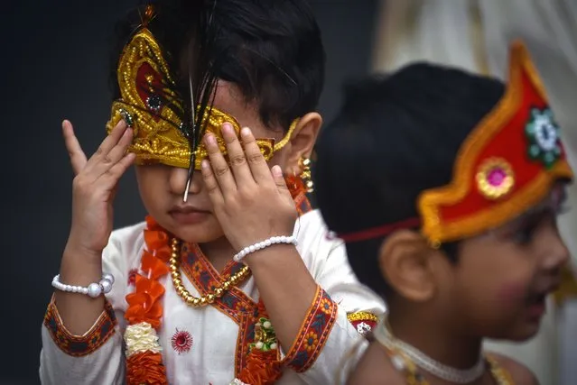 A child dressed as Hindu god Lord Krishna adjusts his colorful headgear while taking part in the celebrations on the eve of the Krishna Janmashtami festival in Chennai, India, 18 August 2022. The festival celebrates the birth of the Hindu god Lord Krishna, one of the most popular gods in Hinduism. (Photo by Idrees Mohammed/EPA/EFE)