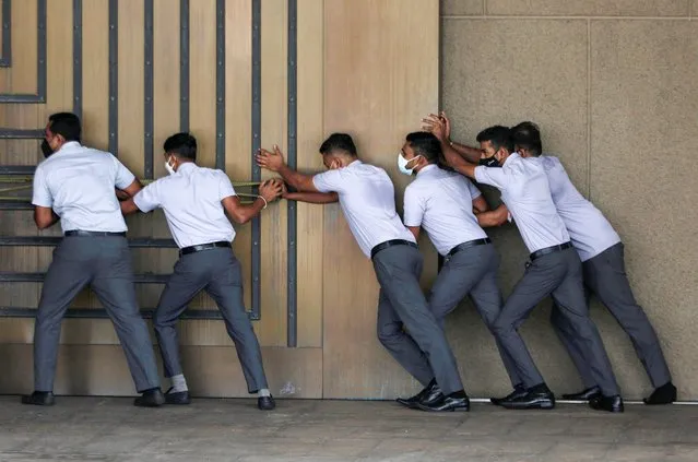 Staff of Sri Lanka's parliament try to open the main door before the Sri Lanka's President Ranil Wickremesinghe arrives to inaugurate a new session of parliament and deliver his first policy statement, amid the country's economic crisis, in Colombo, Sri Lanka on August 3, 2022. (Photo by Dinuka Liyanawatte/Reuters)