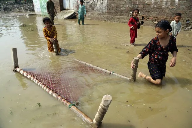 Children salvage a cot from their flood-hit home, in Charsadda, Pakistan, Wednesday, August 31, 2022. Officials in Pakistan raised concerns Wednesday over the spread of waterborne diseases among thousands of flood victims as flood waters from powerful monsoon rains began to recede in many parts of the country. (Photo by Mohammad Sajjad/AP Photo)
