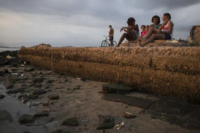 Girls chat as they sit near the shores of of Guanabara Bay, the venue for sailing at the 2016 Summer Olympic Games, in Rio de Janeiro, Brazil, Saturday, July 30, 2016. The international sporting event is fast approaching, with the opening ceremony less than a week away. (Photo by Felipe Dana/AP Photo)