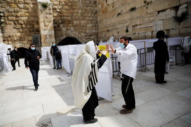 A man blocks a worshipper from getting closer to the Western Wall, Judaism's holiest prayer site, where partitioned areas were set for worshippers to adhere to coronavirus (COVID-19) restrictions on large gatherings, in Jerusalem on May 6, 2020. (Photo by Ronen Zvulun/Reuters)