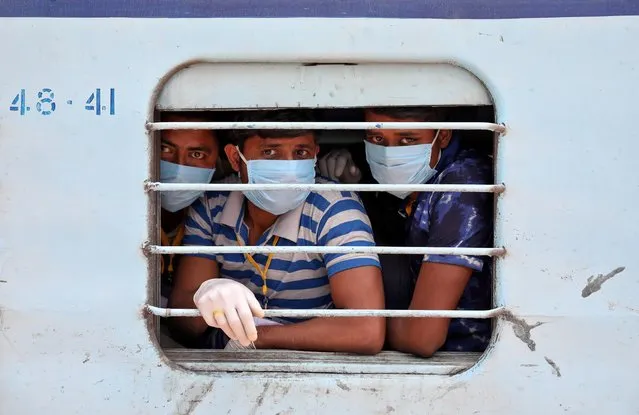 Migrant workers, who were stranded in the western state of Rajasthan due to a lockdown imposed by the government to prevent the spread of coronavirus disease (COVID-19), wear protective masks as they look out from a window of a train upon their arrival in their home state of eastern West Bengal, at a railway station on the outskirts of Kolkata, India, May 5, 2020. (Photo by Rupak De Chowdhuri/Reuters)
