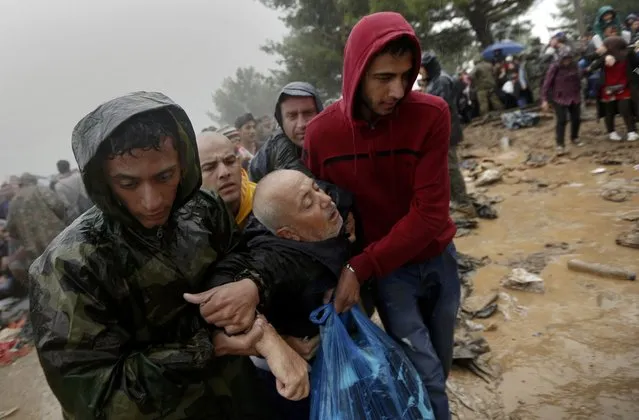 Syrian refugees carry a sick man as they walk through the mud to cross the border from Greece into Macedonia during a rainstorm, near the Greek village of Idomeni, September 10, 2015. (Photo by Yannis Behrakis/Reuters)