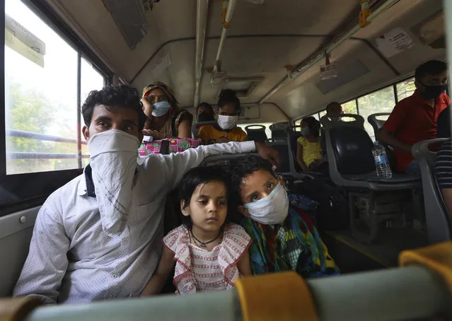 A migrant family from another state trying to return to their villages waits in bus to be transported to a railway station in New Delhi, India, Monday, May 18, 2020. India has recorded its biggest single-day surge in new cases of coronavirus. The surge in infections comes a day after the federal government extended a nationwide lockdown to May 31 but eased some restrictions to restore economic activity and gave states more control in deciding the nature of the lockdown. (Photo by Manish Swarup/AP Photo)