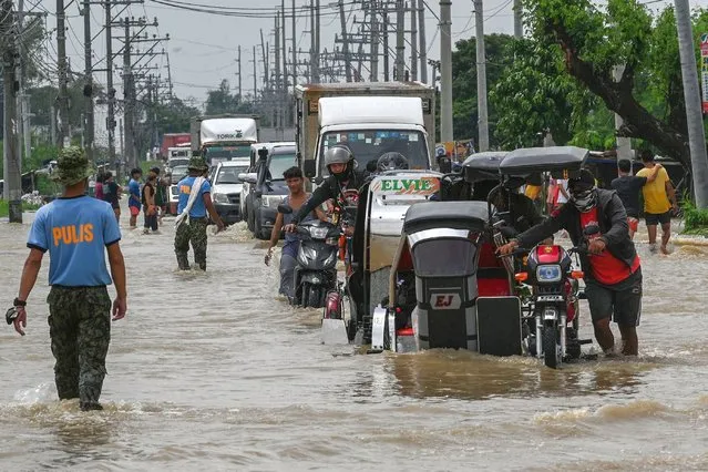 Residents and motorists commute along a flooded highway in the aftermath of Super Typhoon Noru in San Ildefonso, Bulacan province on September 26, 2022. (Photo by Ted Aljibe/AFP Photo)