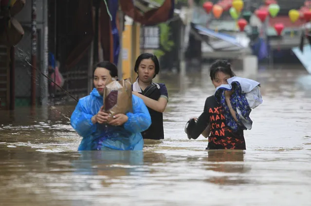 People wade through flooded street of Hoi An ancient town, Vietnam, Monday, November 6, 2017. Typhoon Damrey has killed dozens of people, and left more than a dozen missing and caused extensive damage to the country's south central region ahead of APEC summit that will draw leaders from around the world, the government said Monday. (Photo by Hau Dinh/AP Photo)