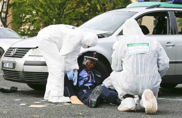 German police criminal experts investigate during a drill of a mock terrorist attack at police training grounds in Berlin, Germany, September 16, 2015. Berlin's police on Wednesday conducted a training on a crime scene simulating an investigation after a terrorist attack. (Photo by Fabrizio Bensch/Reuters)