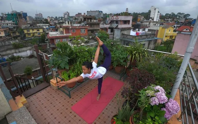 Yoga instructor Suzana Pradhan performs a yoga posture at a rooftop in her house during International Yoga Day, in Kathmandu on June 21, 2020. (Photo by Prakash Mathema/AFP Photo)
