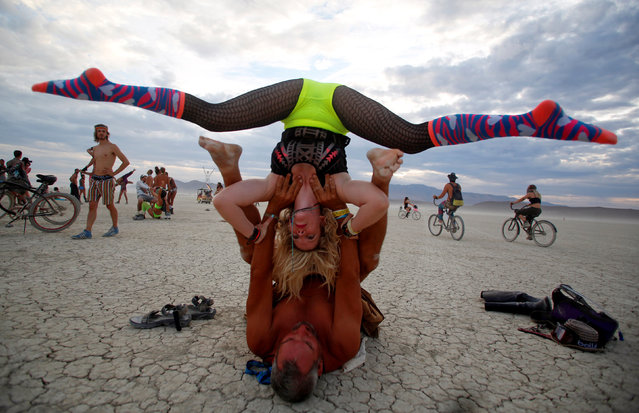 Mark Dill and Brit Thacker practice acro-yoga as approximately 70,000 people from all over the world gather for the 30th annual Burning Man arts and music festival in the Black Rock Desert of Nevada, U.S. August 29, 2016. (Photo by Jim Urquhart/Reuters)