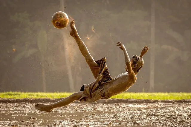 Kids seem to have their own “golden boots” as they have a kickabout in a field of mud. The boys were spotted getting caked in mud by Erwin Gucci, 46 when he visited the village of Rumpin in Bogor, West Java, Indonesia in October 2022. (Photo by Erwin Gucci/Solent News & Photo Agency)
