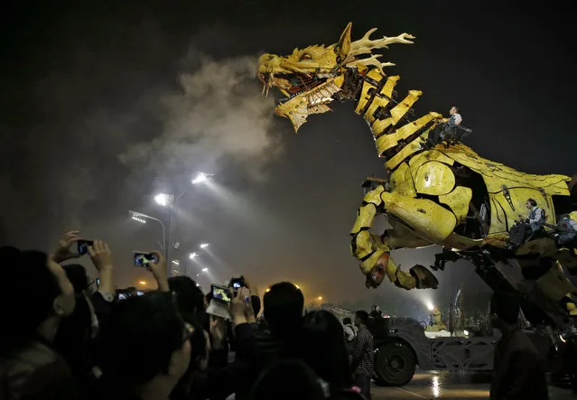 People take photos while the French production company La Machine's latest creation “The Long Ma” or Dragon Horse appears during a performance held in front of the Bird's Nest Stadium in Beijing, China Sunday, Oct. 19, 2014. The performance, which attended by French Foreign Minister Laurent Fabius and his Chinese counterpart Wang Yi, mark the climax of celebrations for the 50th anniversary of Sino-French diplomatic relations. (Photo by Andy Wong/AP Photo)