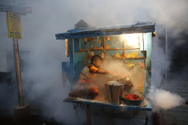 A man who sells chewable tobacco covers his items as a municipal worker fumigates to prevent mosquitoes from breeding in Lucknow, India, Tuesday, September 22, 2015. Dengue outbreaks are reported every year after the monsoon season that runs from June to September. Many people have died from the mosquito-borne disease in the country's capital New Delhi this year. (Photo by Rajesh Kumar Singh/AP Photo)