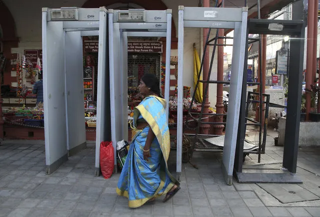 An Indian woman walks past metal detectors which are to be placed on a busy street for New Year's Eve celebrations in Bangalore, India, Sunday, December 31, 2017. (Photo by Aijaz Rahi/AP Photo)