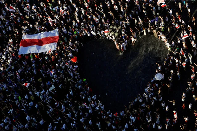 A large historical white-red-white flag of Belarus is pictured next to demonstrators forming a heart during a protest against the results of the Belarusian presidential election in Prague, Czech Republic, August 16, 2020. (Photo by David W. Cerny/Reuters)