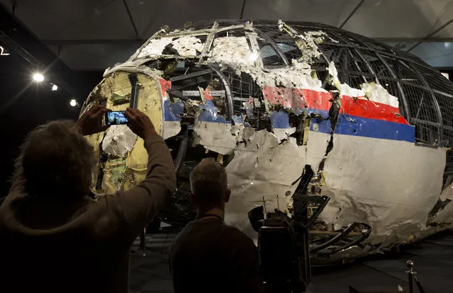 Journalists take images of part of the reconstructed forward section of the fuselage after the presentation of the Dutch Safety Board's final report into what caused Malaysia Airlines Flight 17 to break up high over Eastern Ukraine last year, killing all 298 people on board, during a press conference in Gilze-Rijen, central Netherlands, Tuesday, October 13, 2015. (Photo by Peter Dejong/AP Photo)