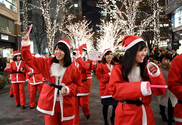 Marunouchi shop clerks and workers wearing Santa Claus costumes join a Christmas parade at the Marunouchi shopping district in Tokyo on December 22, 2017. (Photo by Toshifumi Kitamura/AFP Photo)