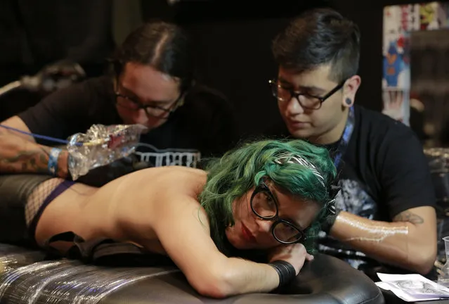 A woman has her back tattooed during the VIII International Convention of Tattoo artists in Bogota, Colombia, Saturday, November 15, 2014. (Photo by Fernando Vergara/AP Photo)