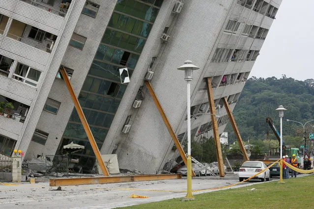 Rescue workers stand next to a damaged building in Hualien, Taiwan February 7, 2018. (Photo by Reuters/Stringer)