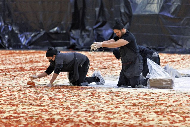 Cooks work inside the Los Angels Convention center as Pizza Hut attempts to create the World's largest pizza of 14,101 square feet in Los Angeles, California, U.S., January 18, 2023. (Photo by Mike Blake/Reuters)