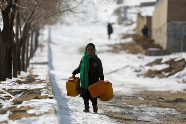 An Afghan girl carries empty water containers on a snow-covered street in Kabul, Afghanistan on January 26, 2023. (Photo by Ali Khara/Reuters)