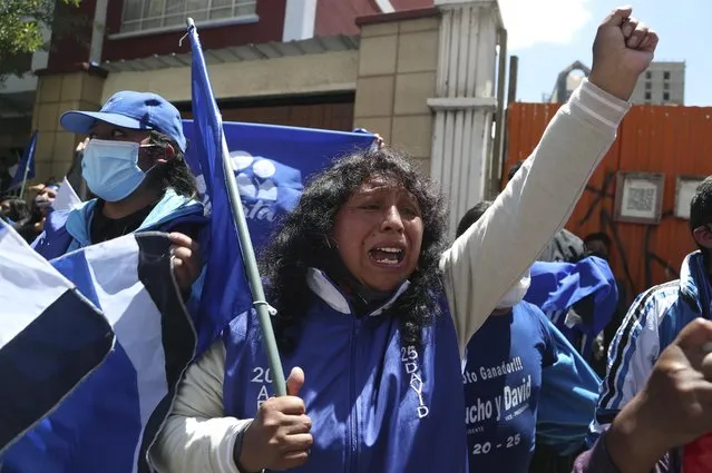 Supporters of presidential candidate Luis Arce shout slogans outside his headquarters one day after elections in La Paz, Bolivia, Monday, October 19, 2020. Evo Morales' party, with Arce as its candidate, claimed victory in a presidential election that appeared to reject the right-wing policies of the interim government that took power in Bolivia after the leftist leader resigned and fled the country a year ago. (Photo by Martin Mejia/AP Photo)