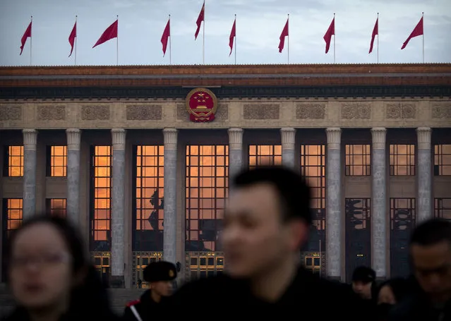 The rising sun is reflected in the windows of the Great Hall of the People as tourists leave Tiananmen Square after the daily flag-raising ceremony at dawn ahead of the opening session of China's National People's Congress (NPC) in Beijing, Monday, March 5, 2018. (Photo by Mark Schiefelbein/AP Photo)