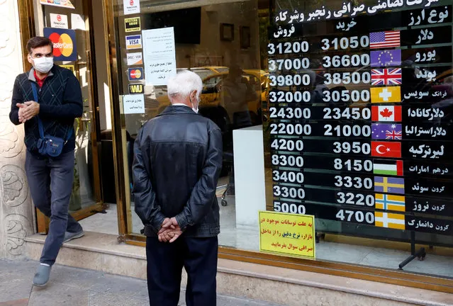 An Iranian man checks the currency rate as he walks past a currency exchange service  in Tehran, Iran, 14 October 2020. Media reported that following tension between Iran and US, the US administration announced more sanctions against Iran causing severe damage to the Iranian economy. (Photo by Abedin Taherkenareh/EPA/EFE/Rex Features/Shutterstock)
