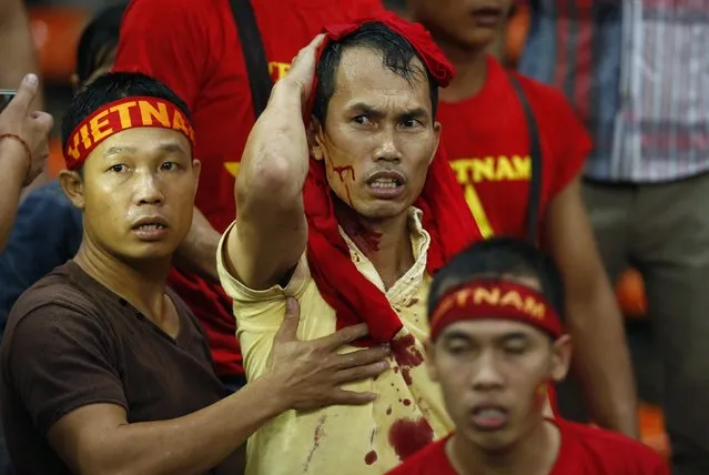 A Vietnamese fan wipes blood on his head after scuffles between fans during the first leg of the Suzuki Cup 2014 semi-final match between Vietnam and Malaysia at Shah Alam stadium in Kuala Lumpur December 7, 2014. (Photo by Olivia Harris/Reuters)