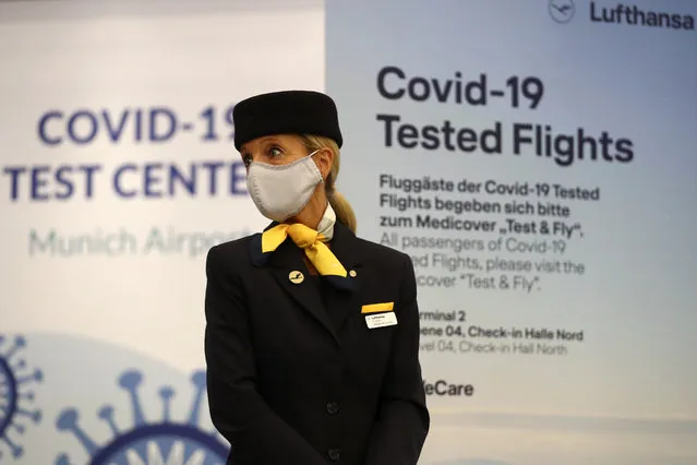 A flight attendant stands in front of the entrance of a new Lufthansa corona quick test center at the airport in Munich, Germany, Thursday, November 12, 2020. Lufthansa starts the first test runs for comprehensive Covid-19 antigen rapid tests on selected routes between Munich and Hamburg. (Photo by Matthias Schrader/AP Photo)