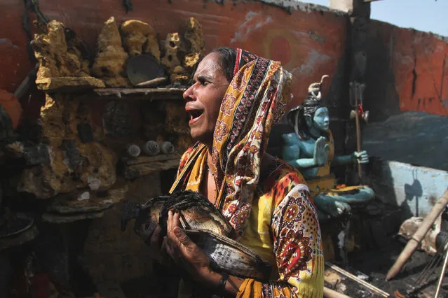 A minority Hindu women cries in a temple as she holds remains of holy book burnt in an accidental fire broke out in slums of  Karachi, Pakistan Thursday, November 5, 2015. Dozens of houses were gutted in the incident. (Photo by Fareed Khan/AP Photo)