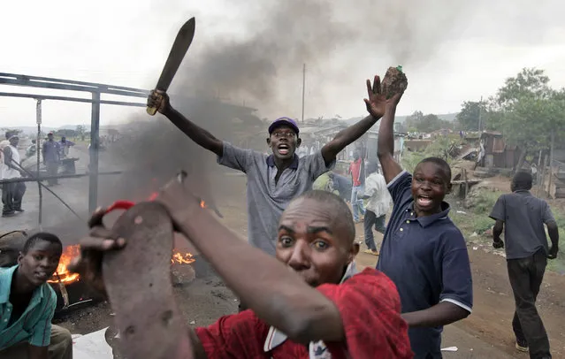 In this Monday, January 28, 2008 file photo, Kenyan men from the Luo tribe armed with machetes and rocks enforce a makeshift roadblock, searching passing vehicles for Kikuyus trying to flee the town in order to kill them, during post-election violence on the main road to the Ugandan border near the airport in Kisumu, Kenya. (Photo by Ben Curtis/AP Photo)