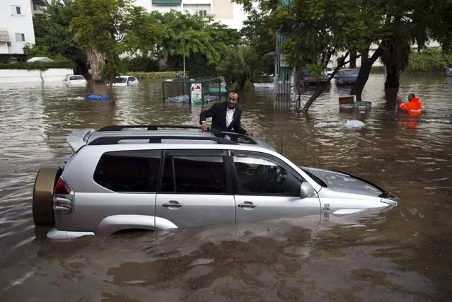 A motorist climbs out of his vehicle after getting stuck on a flooded street in the southern city of Ashkelon, Israel, November 9, 2015. (Photo by Amir Cohen/Reuters)