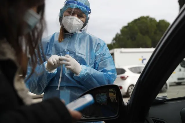 Medical personnel prepares to conduct a COVID-19 rapid test at a drive-through testing site in Athens, Friday, December 11, 2020. Despite five weeks of lockdown measures, coronavirus infections remain high, putting pressure on the country's health system. (Photo by Thanassis Stavrakis/AP Photo)
